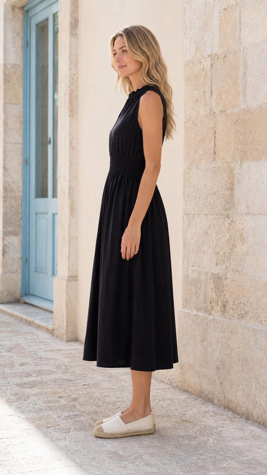 Side profile view of woman in black midi dress outdoors