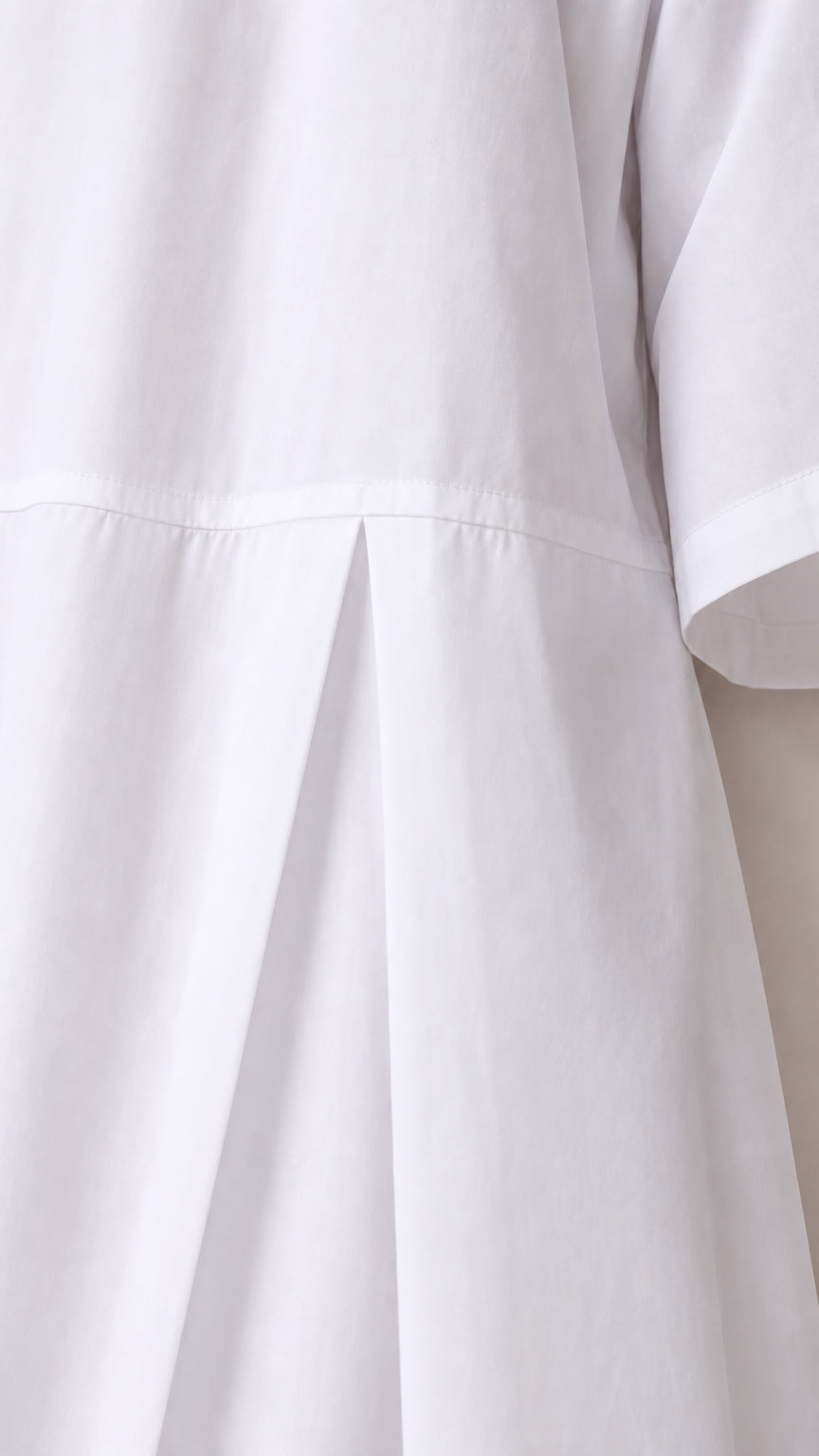 Close-up of pleated dropped waist detail on white dress