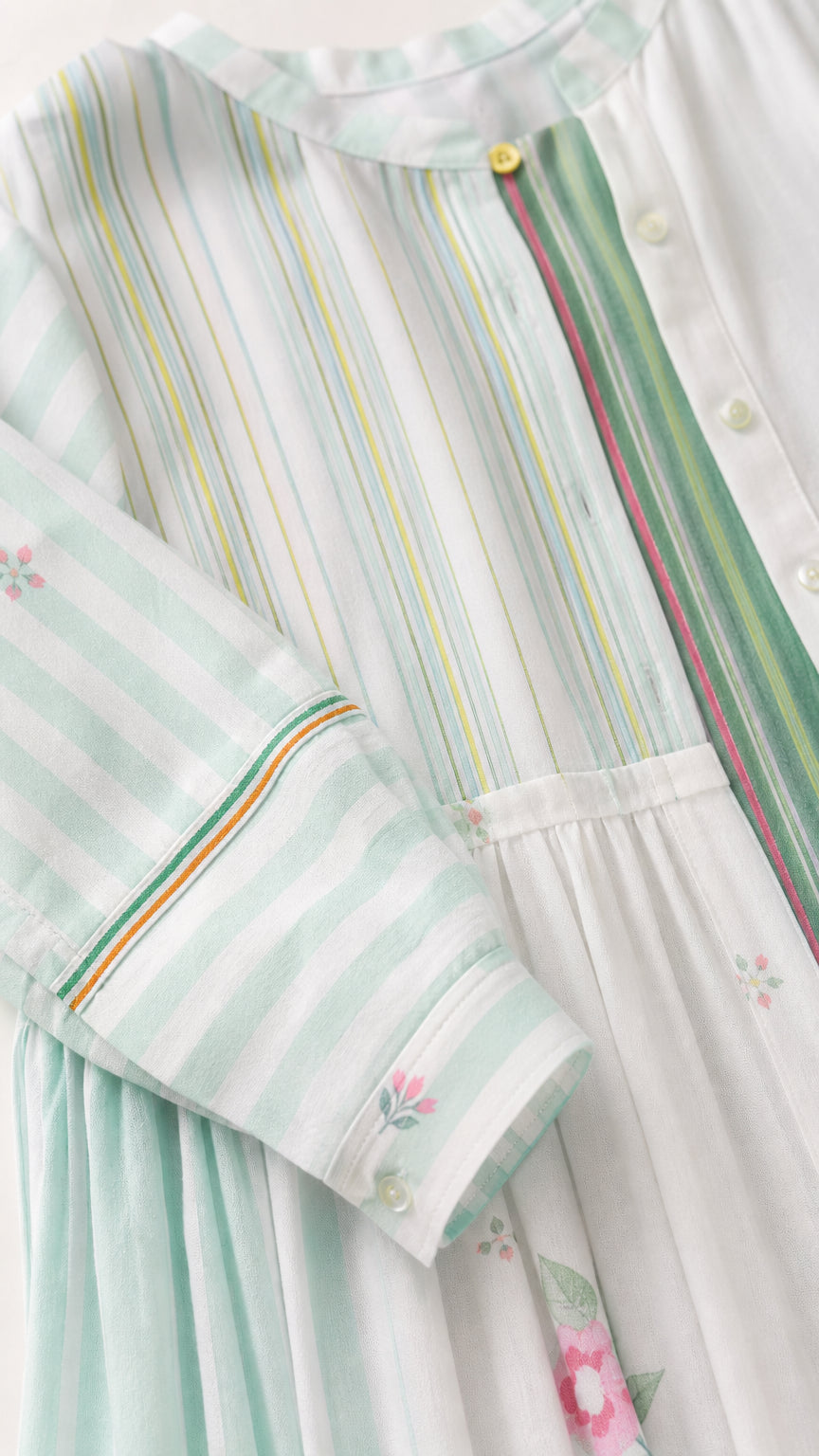 Close-up detail of stripe pattern, buttons, and floral embroidery on sage green set