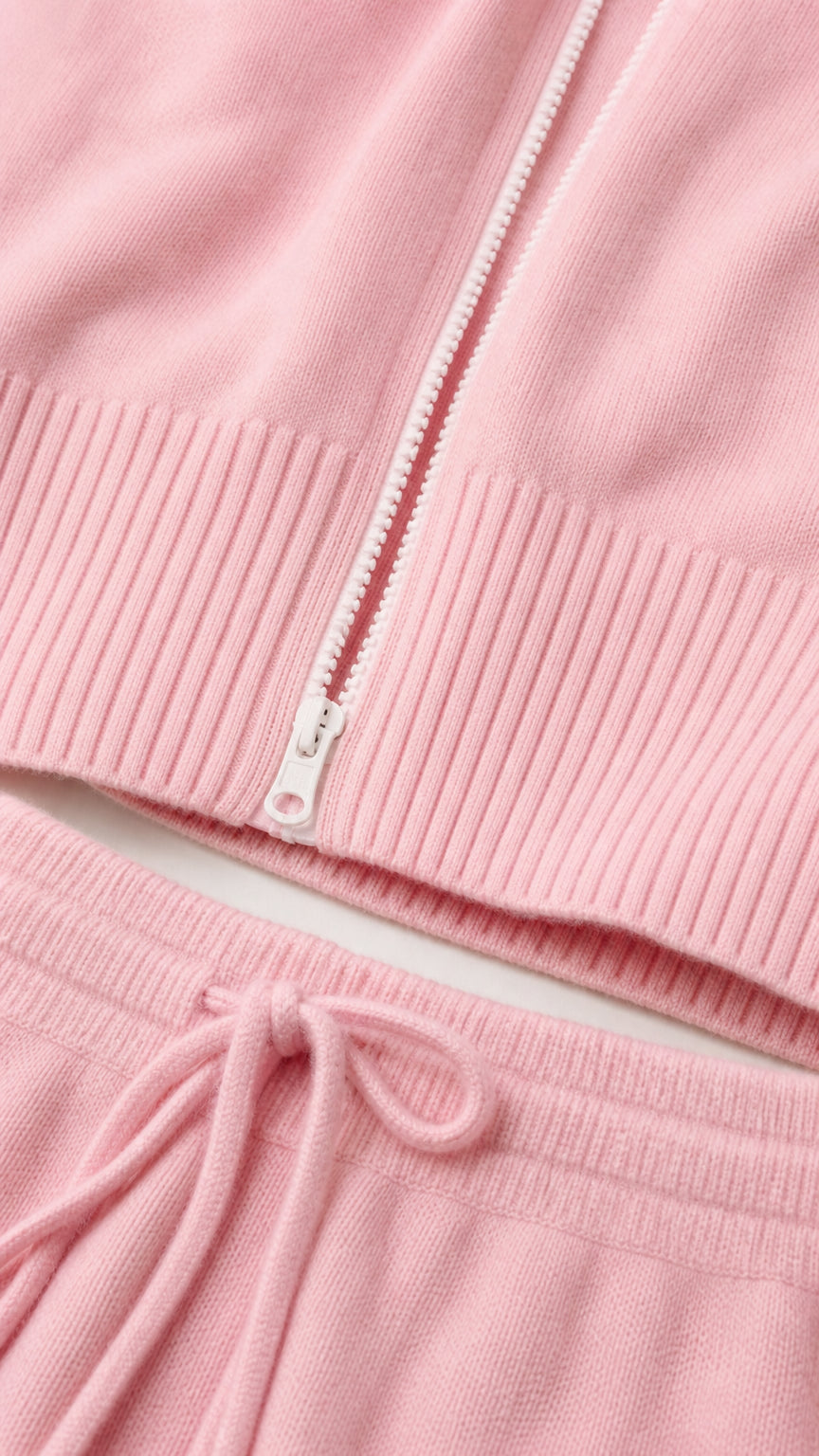 Close-up detail of zipper and drawstring waistband on pink knit set